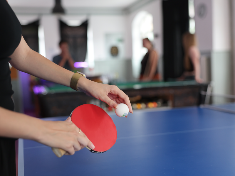 Auf dem Bild ist der Jugendraum in der Linde 13 in Oberndorf am Neckar abgebildet. Der Vordergrund bildet eine Momentaufnahme eine Tischtennisschlägers mit Ball ab. 