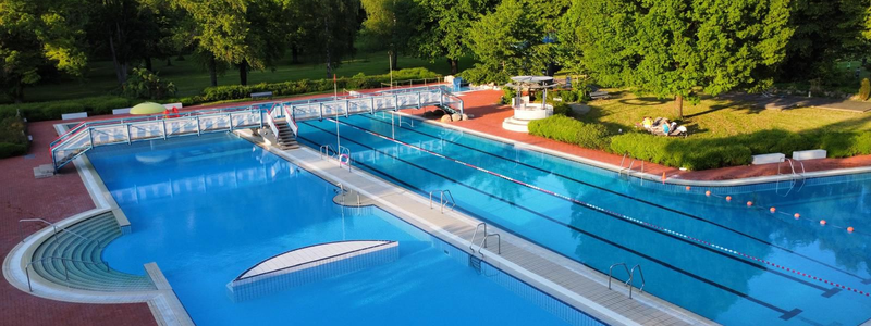Zu sehen ist das Schwimmbecken und das Nichtschwimmerbecken. Über beide Becken führt eine Brücke