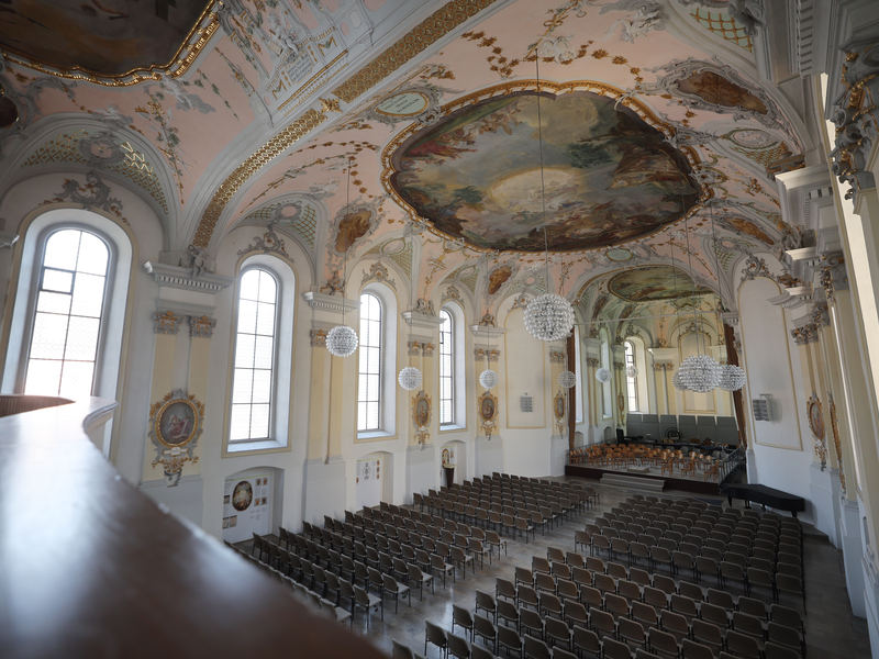 Blick von der Empore der Klosterkirche auf die Bestuhlung und die Tribüne. Festliche runde Leuchte hängen tief  herab. 