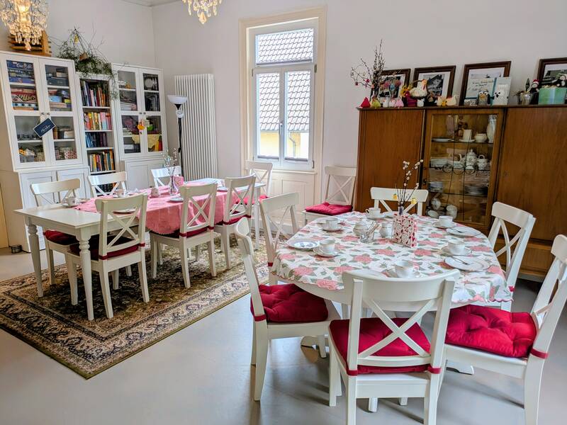 Ein Wohnzimmer mit zwei Tischen und Stühlen und alten Wandschränke